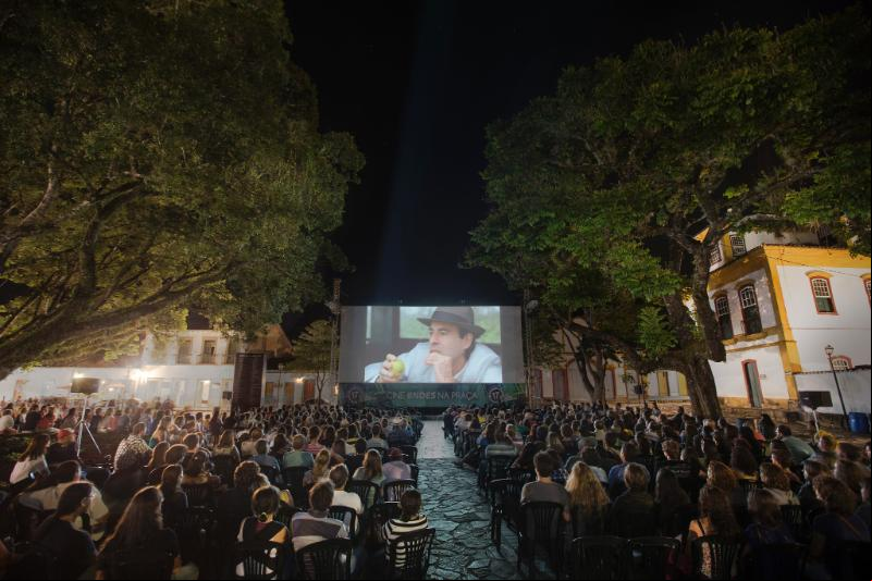 Com o auxílio de um telão, a praça central da cidade de Tiradentes se torna palco de sessões noturnas que comportam mais de mil espectadores